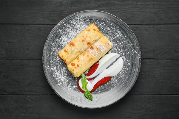 Overhead view of thin crepe with ricotta and strawberry jam on a plate