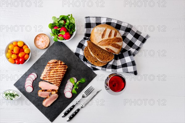 Sliced grilled roast beef with fork and knife on stone serving board. Top view with copy space for your text