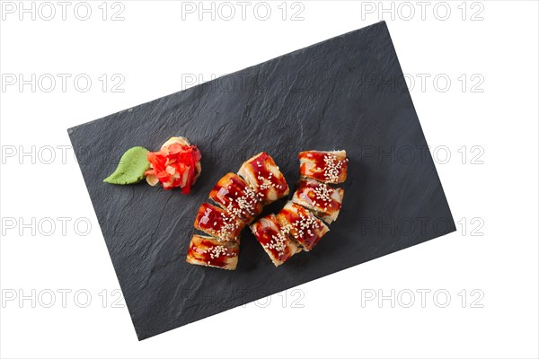 Portion of unagi roll with garnish isolated on white