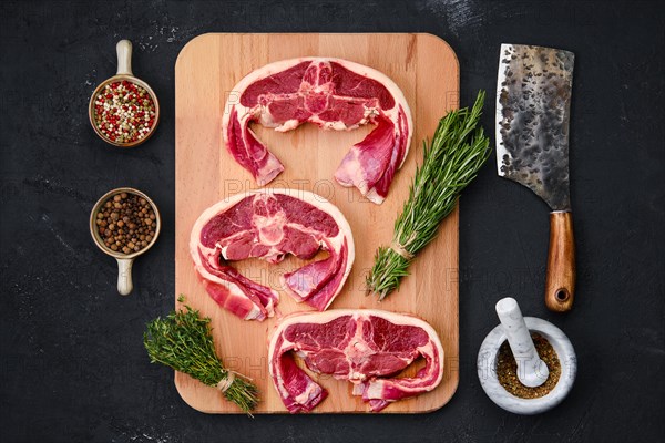 Fresh raw rack of lamb on wooden cutting board with herbs and seasoning