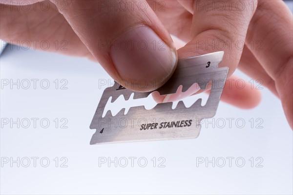 Hand holding a razor blade on a white background