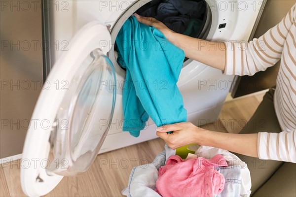 Hands taking laundry out washing machine