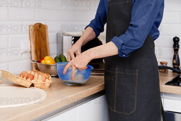 Closeup view of hands of a man whips an egg with a whisk to make an omelet