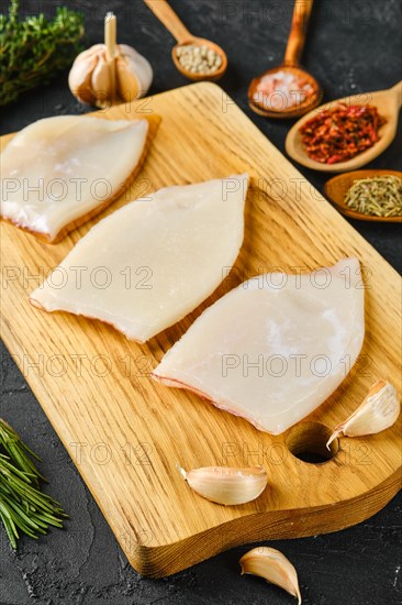 Raw frozen squid fillet on wooden cutting board