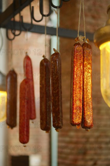 Smoked sausagees hanging on a hook under the ceiling. Photo with shallow depth of field