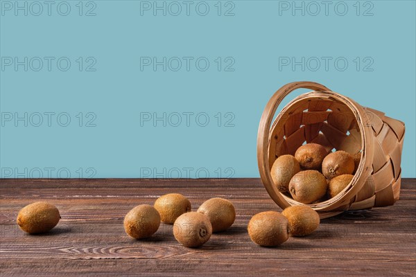 Basket with fresh kiwi on wooden table