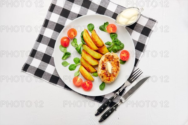 Fried chicken cutlet with potato slices served with tomato cherry and corn salad. Traditional belorussian food