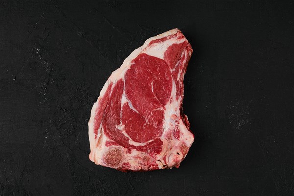 Raw strip steak bone in on dark background