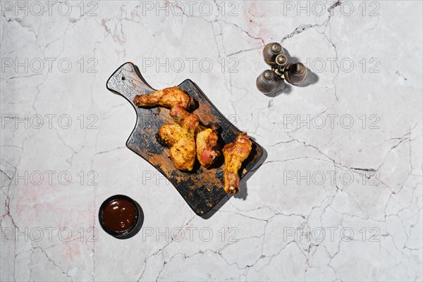 Overhead view of baked crispy chicken legs under hard light