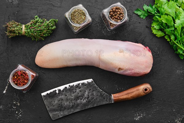 Raw fresh beef tongue with spice and herbs on black background