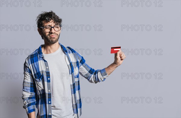 Person holding and looking at credit card with distrust