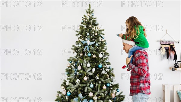 Father daughter decorating christmas tree