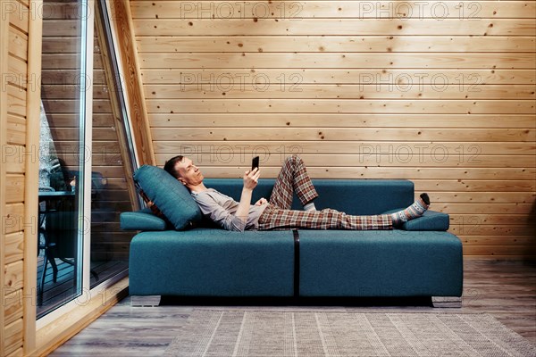 Middle-aged man on couch in his bungalow browsing internet