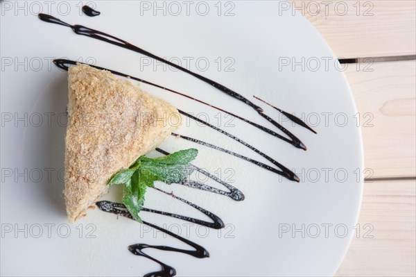 Top view of napoleon cake on plate with chocolate sauce. Puff pastry cake with custard