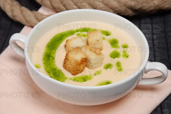 Creamy soup puree in white bowl and small pieces of fried bread toasts