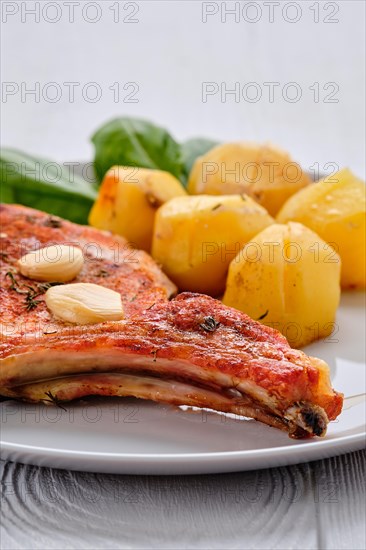 Steak with bone and potato baked in oven in a roasting pan with garlic and thyme