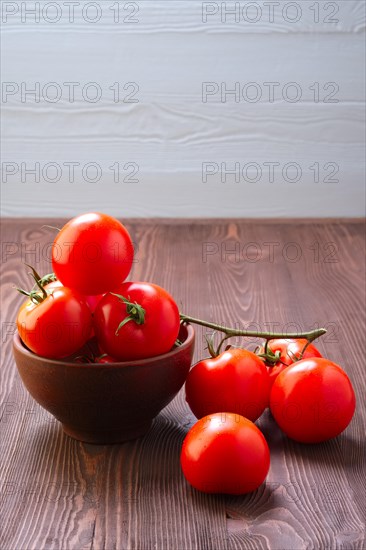 Branch of fresh tomatoes on wooden table