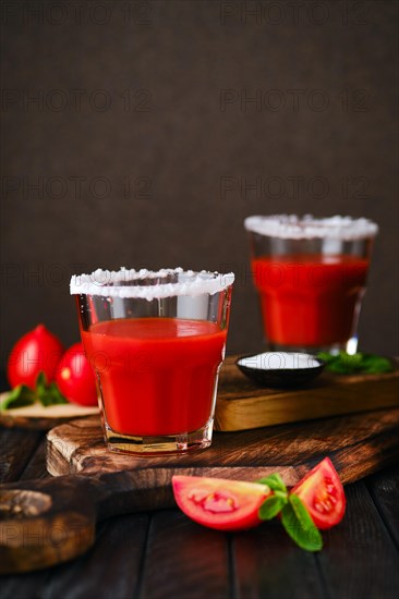 Closeup view of glass with salty tomato juice on dark wooten table