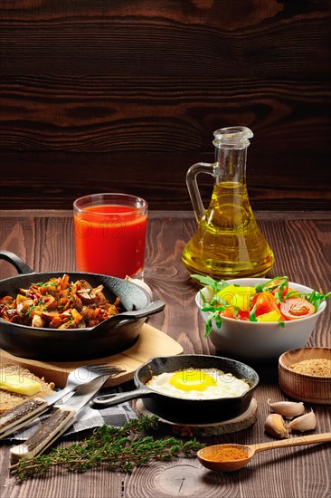 Vegetarian food. Fried mushrooms and egg in cast iron pan. Ingredients for rustic breakfast on wooden table