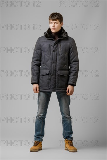 Full length portrait of handsome man in warm winter coat posing in studio