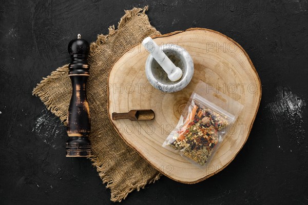 Wooden cross section with set for mulled wine spices in plastic package and stone mortar and mill