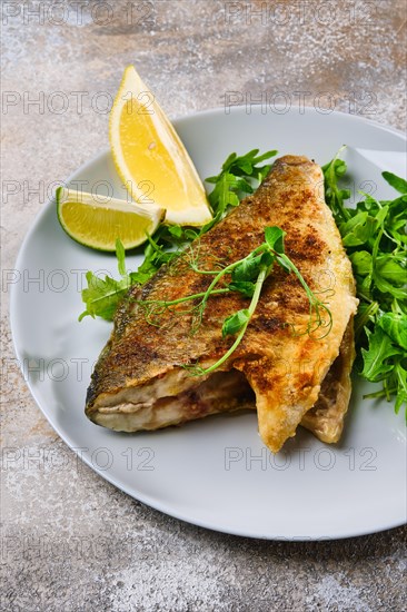 Close up view od fried dorada fish with fresh arugula