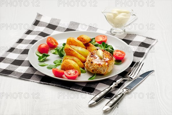 Fried chicken cutlet with potato slices served with tomato cherry and corn salad. Traditional belorussian food