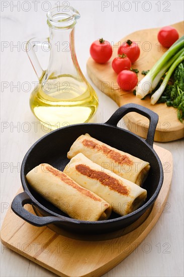 Thin pancakes stuffed with turkey meat in cast iron skillet