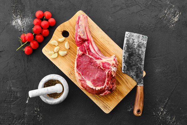 Top view of beef ribeye steak bone-in with spice on black background