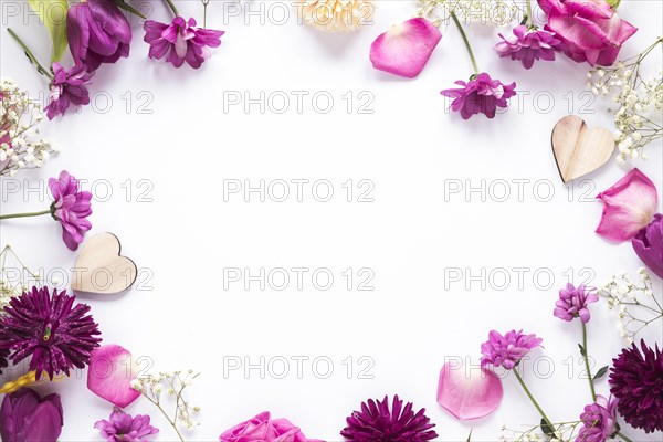 Different flowers with wooden hearts table