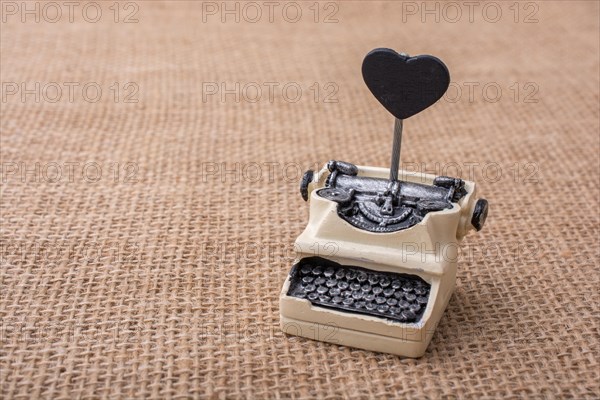 Retro syled tiny typewriter model on a canvas background