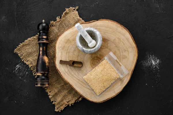 Wooden cross section with garlic in plastic package and stone mortar and mill