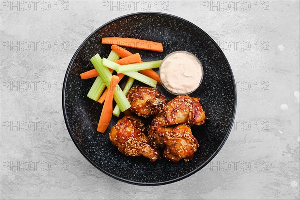 Fried chicken legs with teriyaki sauce and slices of celery and carrot on a plate