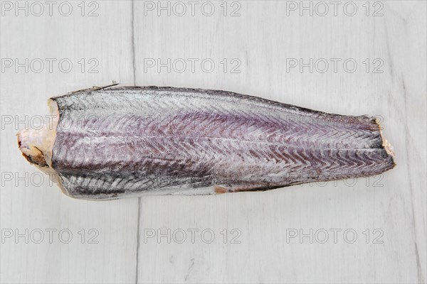 Frozen raw hake carcass on wooden table