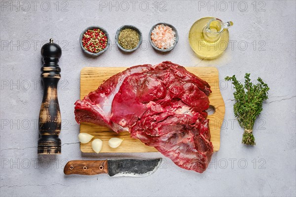 Overhead view of raw fresh deer boneless ham with spice and herb over concrete background