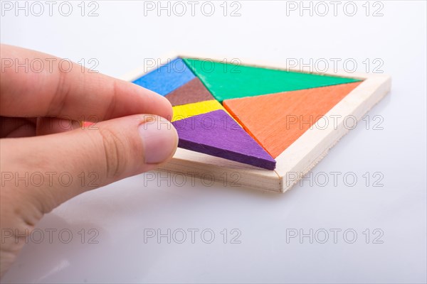 Hand holding a missing piece in a tangram puzzle