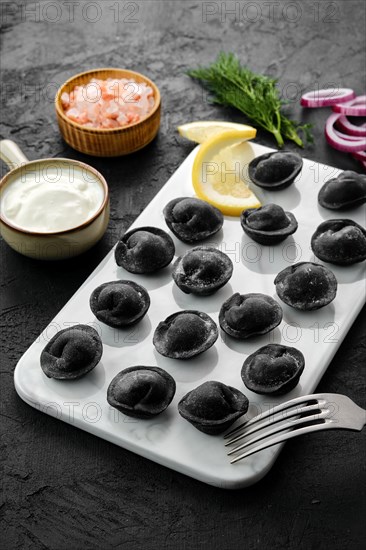 Black dumplings with beef with dough with cuttlefish ink on marble plate