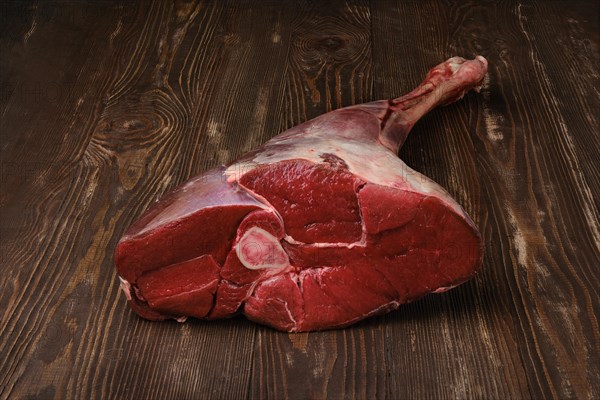 Raw fresh young beef leg on wooden background