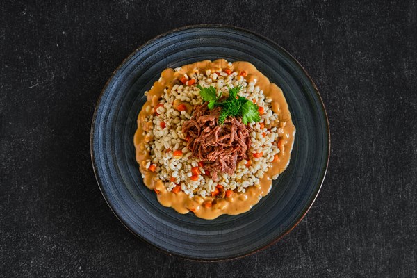 Top view of pulled beef with pearl barley and creamy sauce