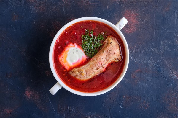 Top view of beet and tomato soup with beef rib and sour cream