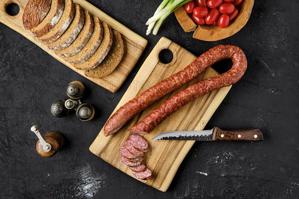 Overhead view of smoked pork sausage rings on wooden cutting board on kitchen table