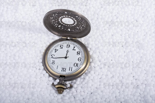 Retro pocket watch on white polystyrene balls