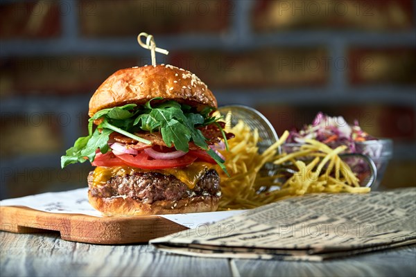 Tasty burger with bacon served with red cabbage salad and french fries