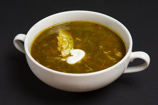 Bowl with pickle soup with egg and sour cream on black background