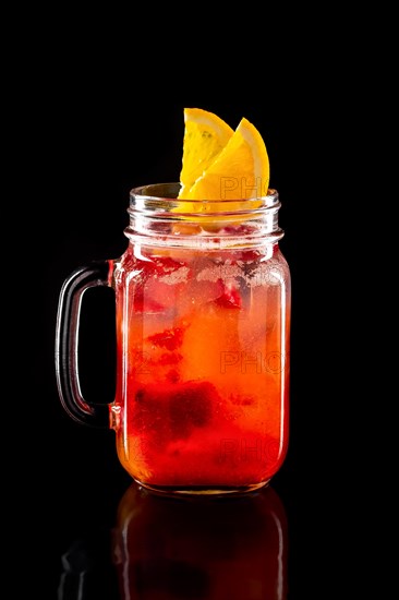 Cold fruit lemonade in mason jar isolated on black background