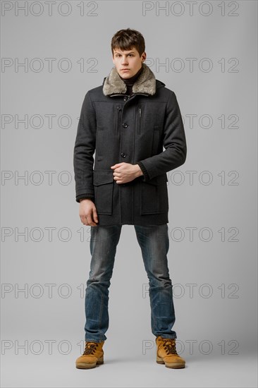 Full length portrait of handsome man in warm winter coat posing in studio