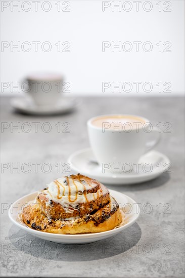 Cappuccino and rolled bun with caramel on a table