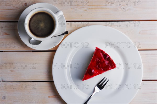 Top view of wooden table with cup of coffee and cherry cheesecake