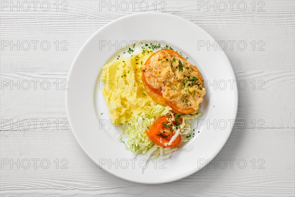 Top view of plate of chopped meat backed with tomato with buckwheat and cabbage salad