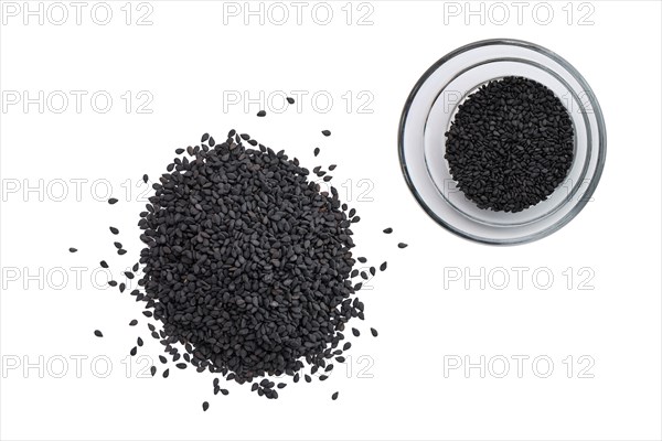 Top view of black sesame seeds in a little bowl and spilled on white background